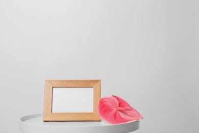 Photo of Blank frame and flower on table against white background. Mock up for design