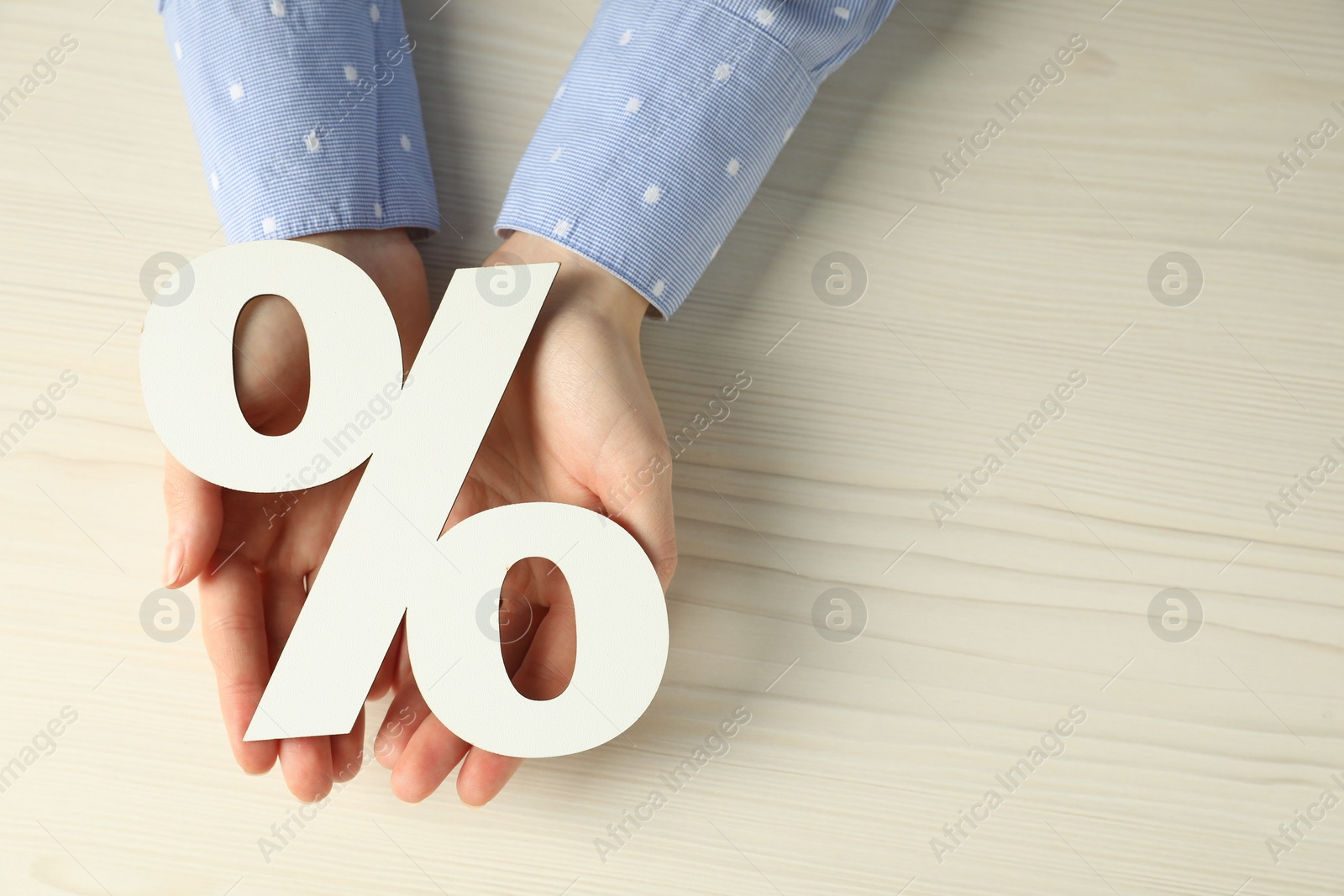 Photo of Woman holding percent sign at white wooden table, top view. Space for text