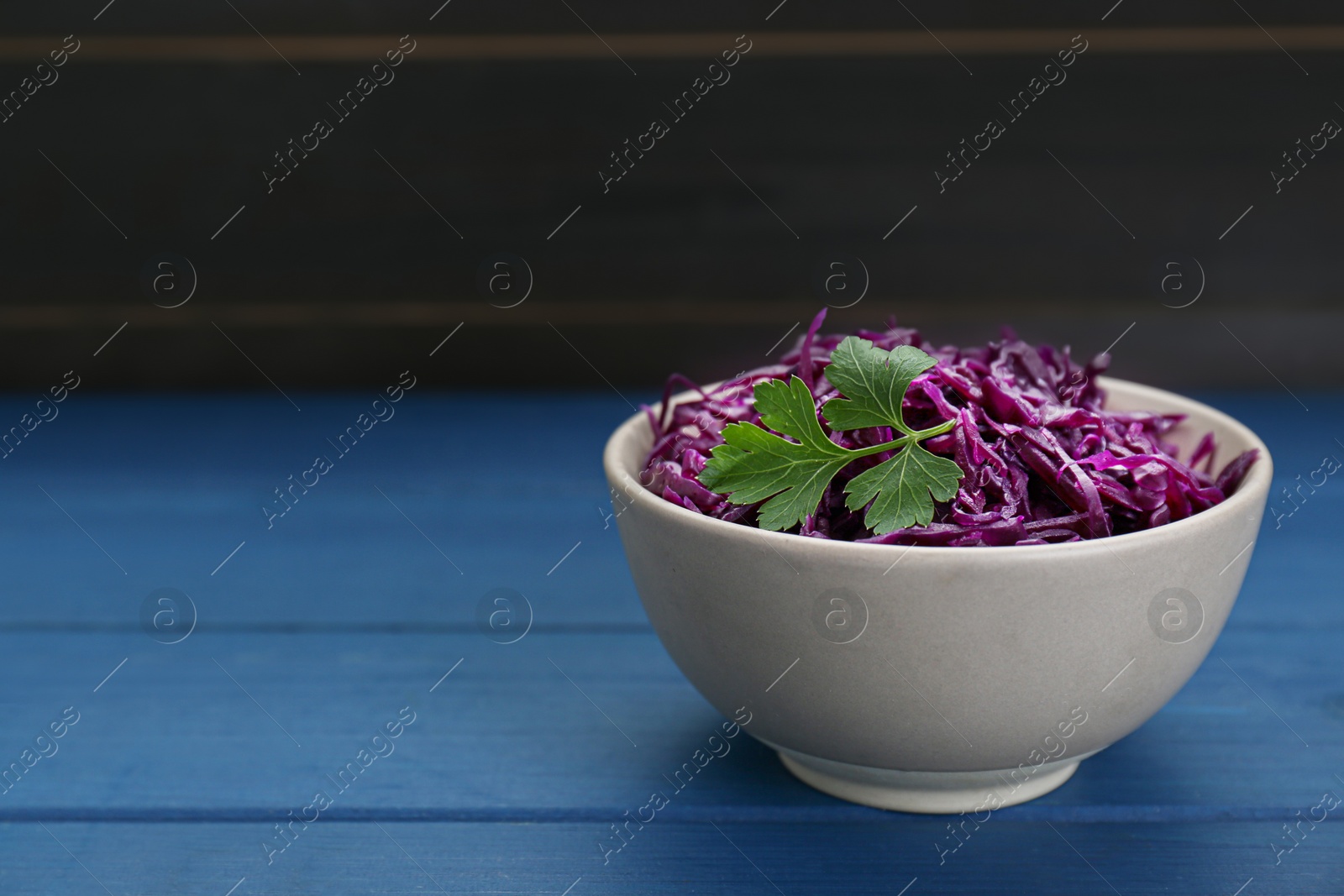 Photo of Tasty red cabbage sauerkraut with parsley on light blue wooden table. Space for text