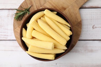 Photo of Tasty fresh yellow baby corns in bowl on white wooden table, top view