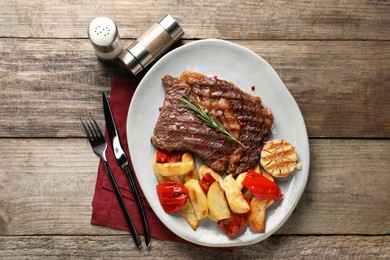 Photo of Delicious grilled beef steak and vegetables served on wooden table, top view