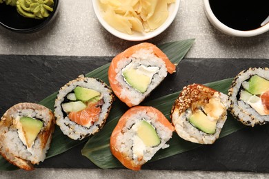 Delicious sushi rolls on light grey table, flat lay