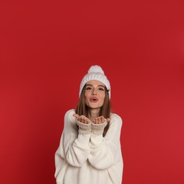 Photo of Beautiful young woman in white sweater and hat on red background. Winter season