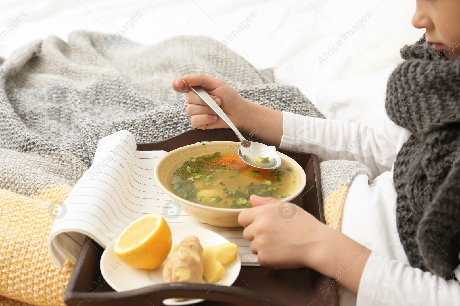 Photo of Sick little boy eating broth to cure cold in bed at home