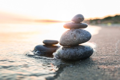 Photo of Dark stones on sand near sea at sunset. Zen concept