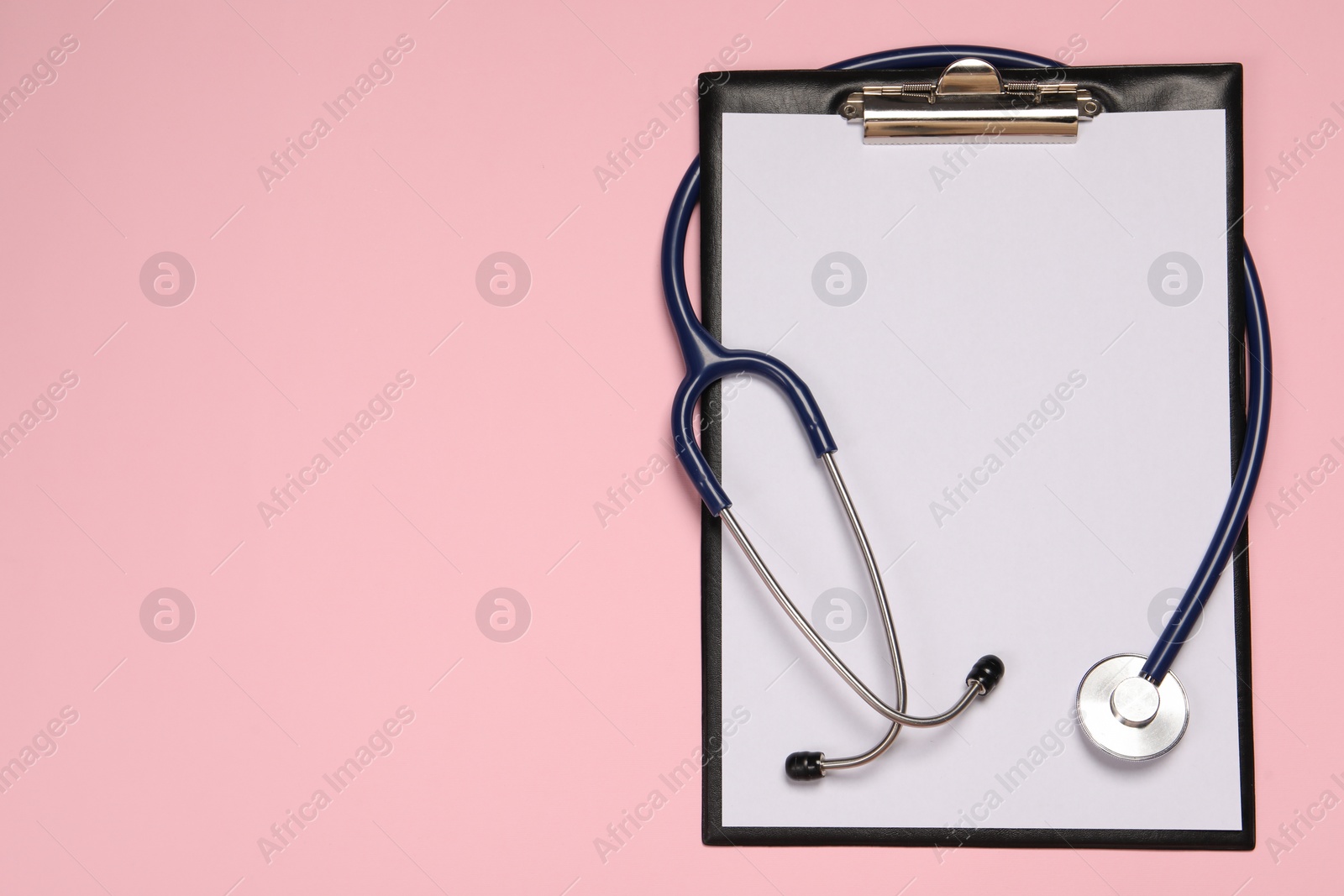 Photo of Stethoscope and clipboard on pink background, top view. Space for text