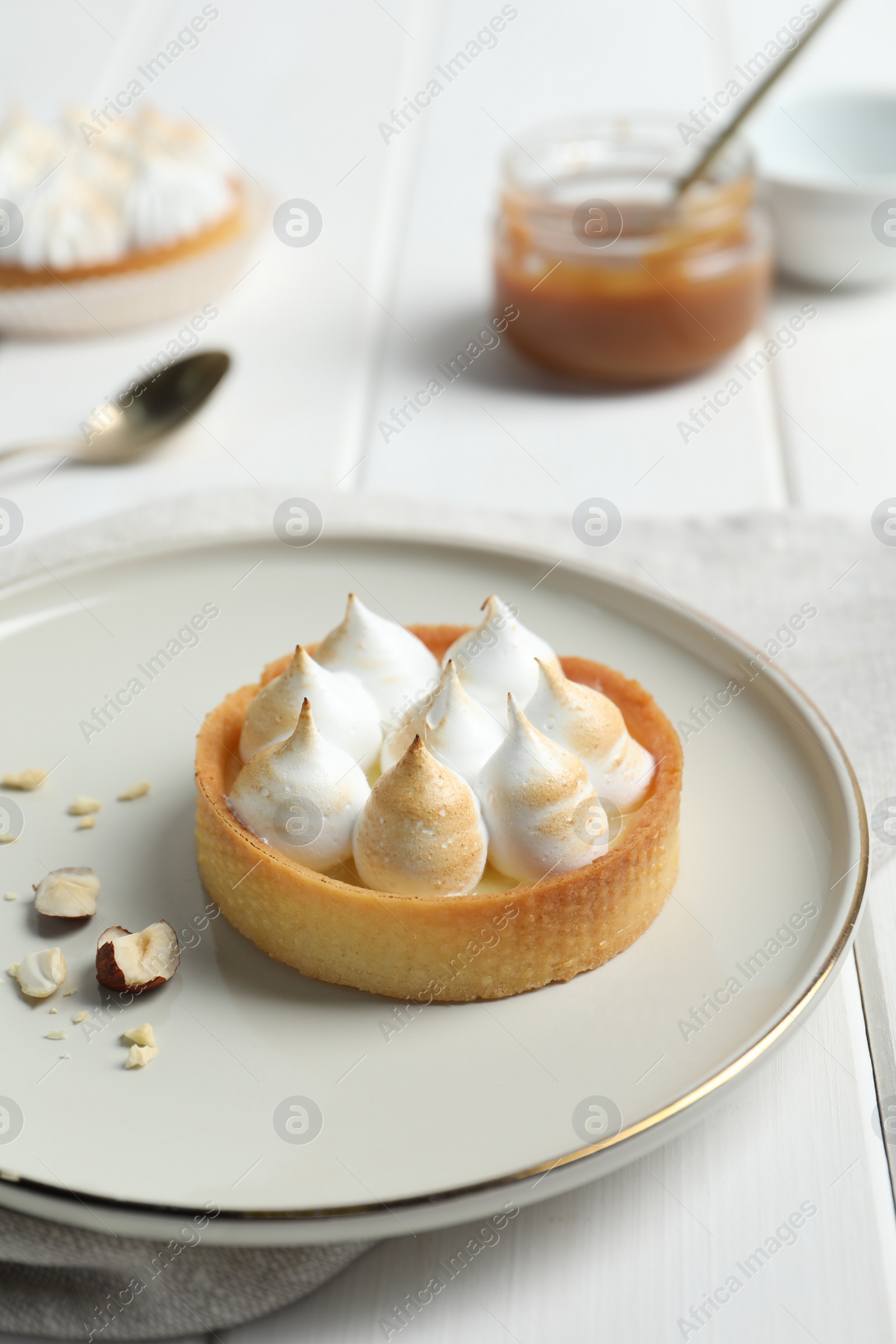 Photo of Tartlet with meringue on white wooden table. Delicious dessert