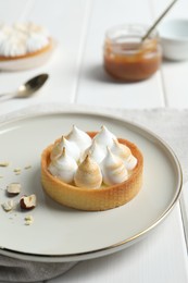 Tartlet with meringue on white wooden table. Delicious dessert
