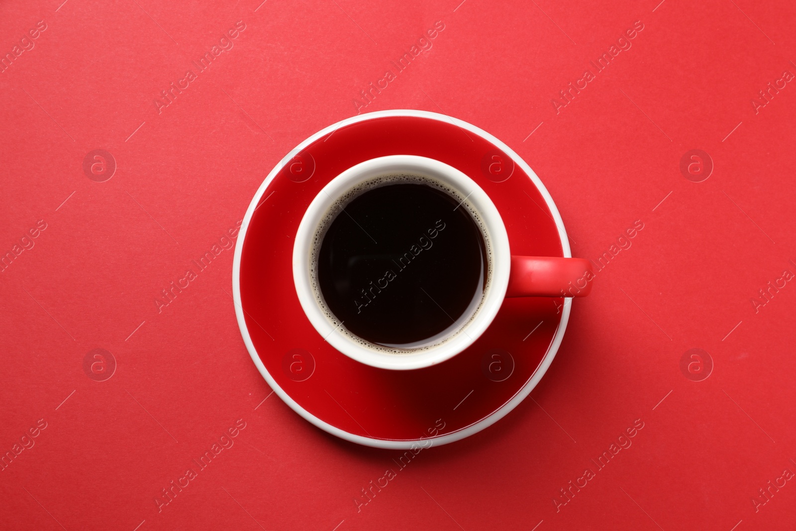 Photo of Aromatic coffee in cup on red background, top view