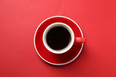 Aromatic coffee in cup on red background, top view