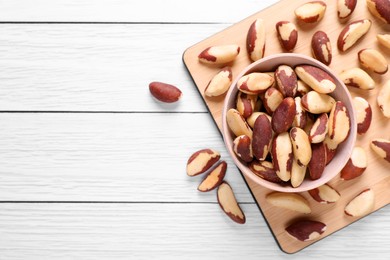 Delicious Brazil nuts on white wooden table, flat lay. Space for text