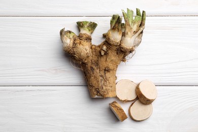 Photo of Cut horseradish root on white wooden table, flat lay