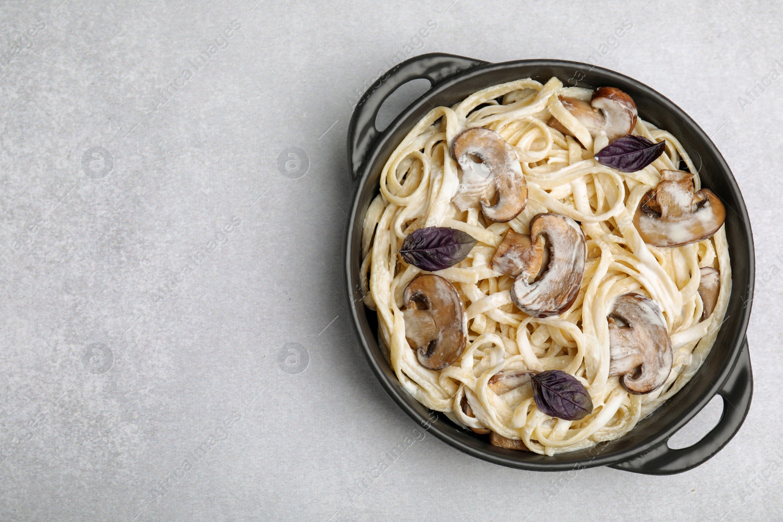 Photo of Delicious pasta with mushrooms on light grey table, top view. Space for text