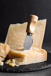 Photo of Parmesan cheese with knife on grey table