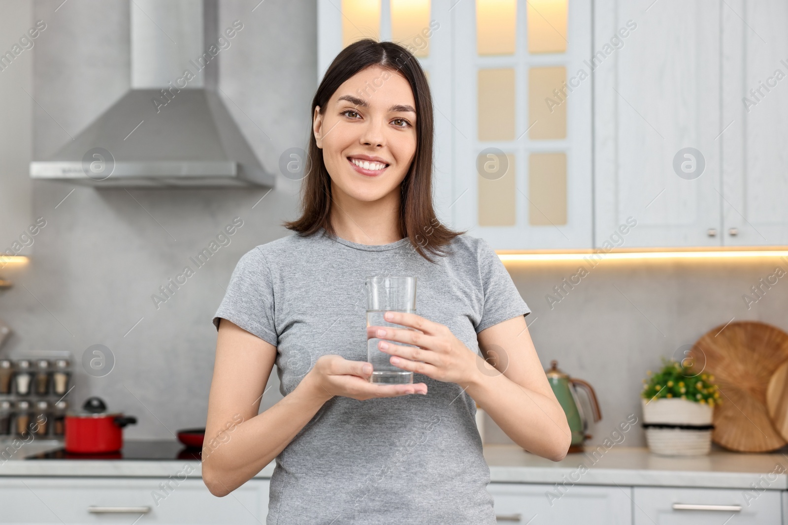 Photo of Woman with glass of fresh water in kitchen