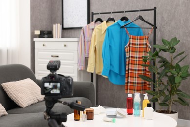 Beauty blogger's workplace. Cosmetic products, camera and clothes indoors
