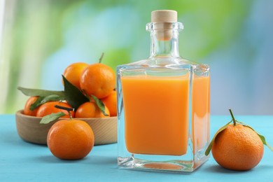 Photo of Delicious tangerine liqueur and fresh fruits on light blue wooden table