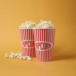 Photo of Delicious popcorn in paper cups on yellow background