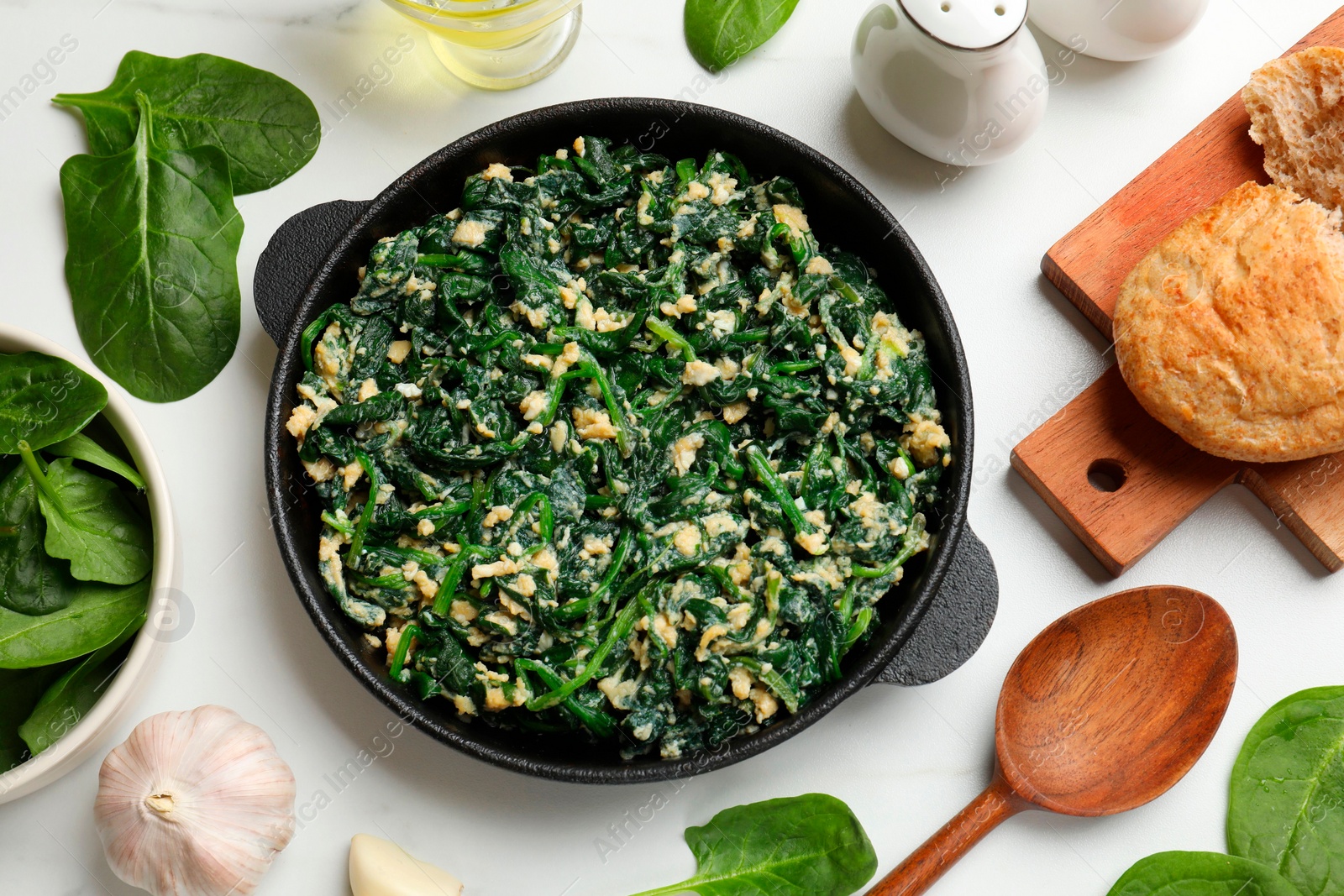 Photo of Tasty spinach dip with eggs in dish served on white table, flat lay