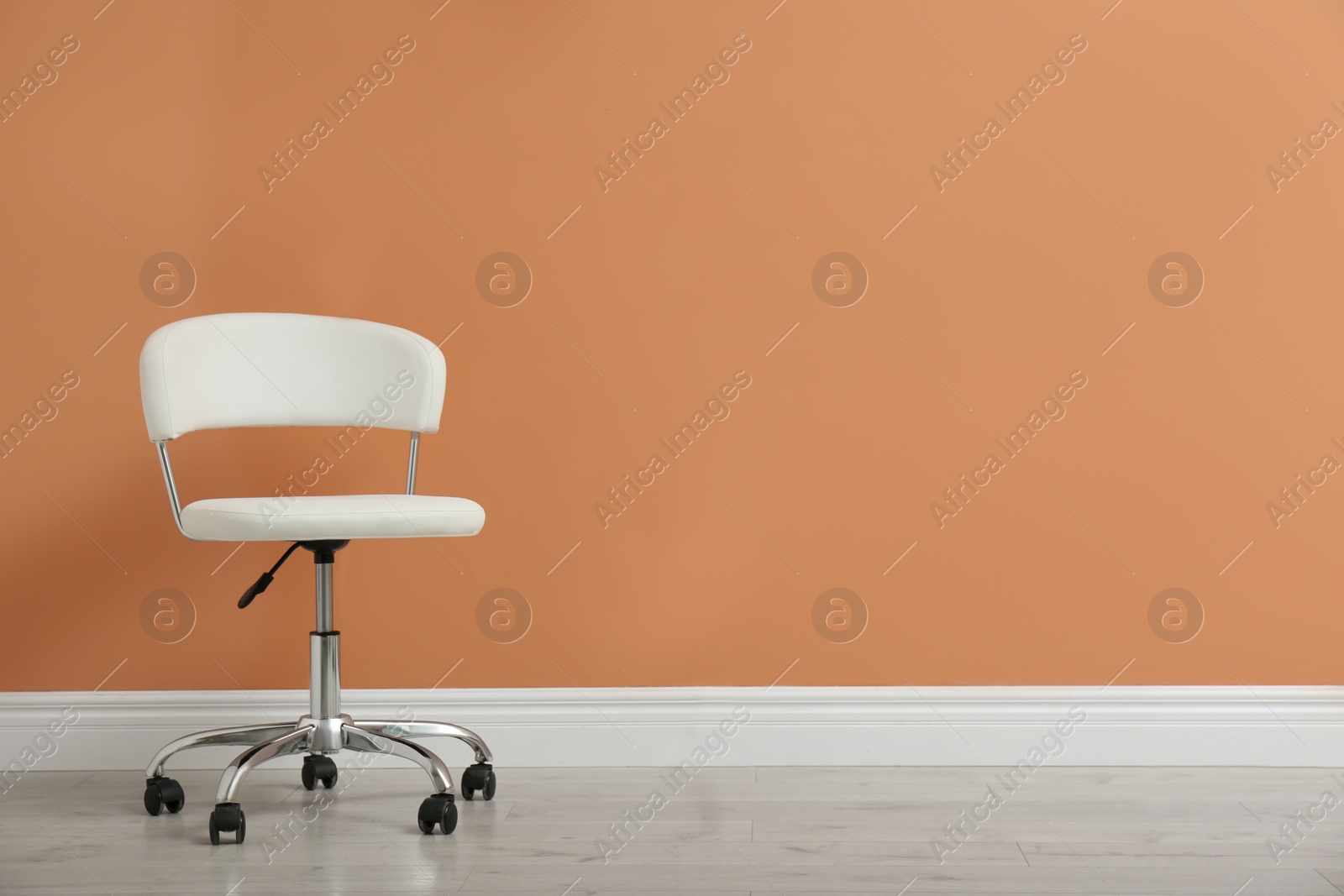 Photo of Modern office chair near orange coral wall indoors. Space for text