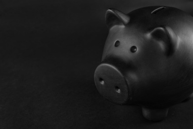 Photo of Black piggy bank on table against dark background