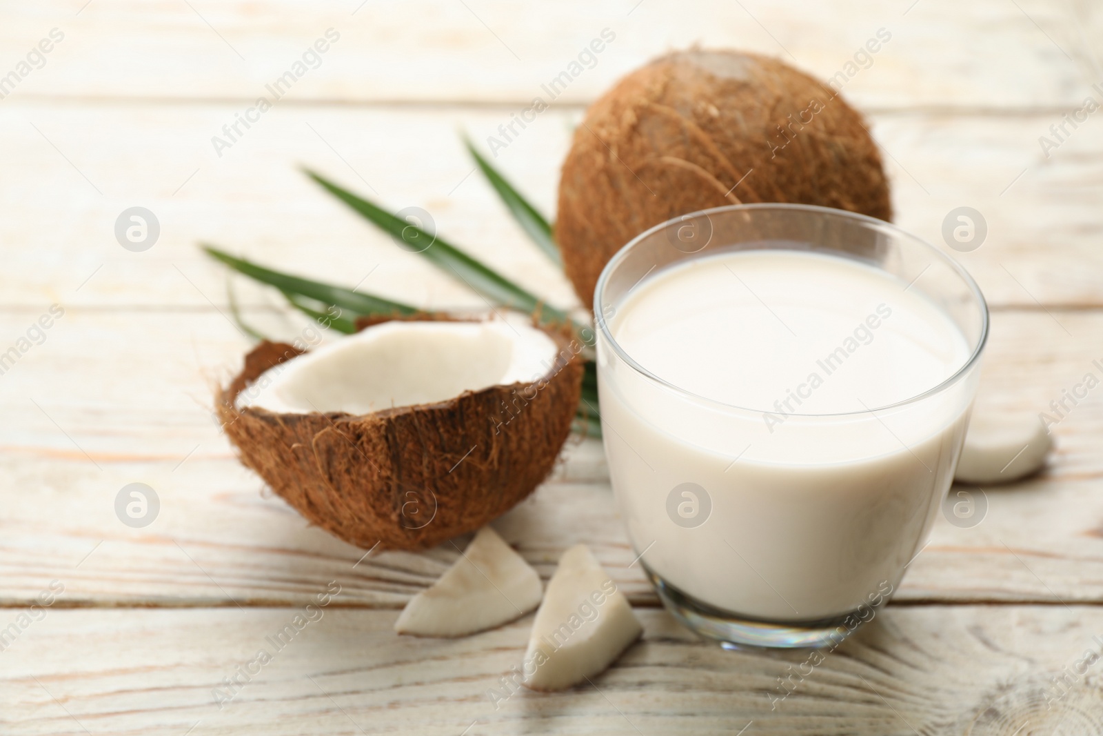 Photo of Delicious vegan milk and coconuts on white wooden table, closeup