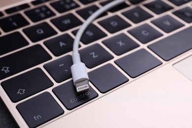 Photo of USB cable with lightning connector and laptop keyboard, closeup