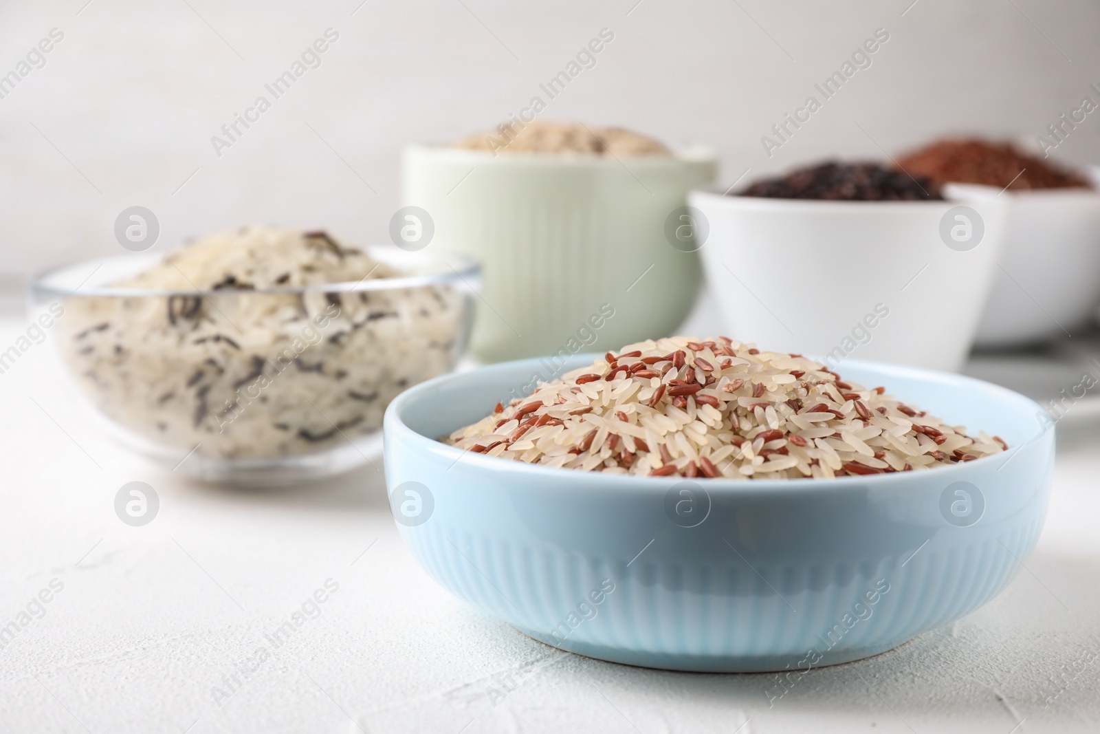 Photo of Mix of brown and polished rice on white table, closeup