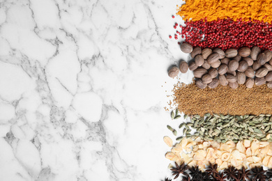 Many different spices on white marble background, top view. Space for text