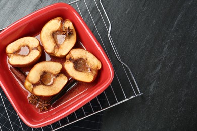 Photo of Tasty baked quinces with anise and honey in dish on black table, top view. Space for text
