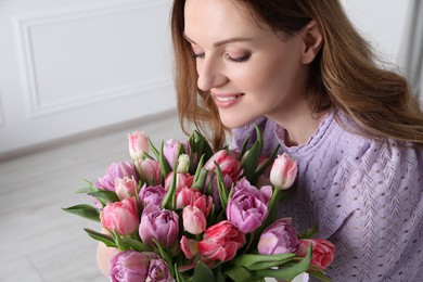 Young woman with bouquet of beautiful tulips indoors, closeup