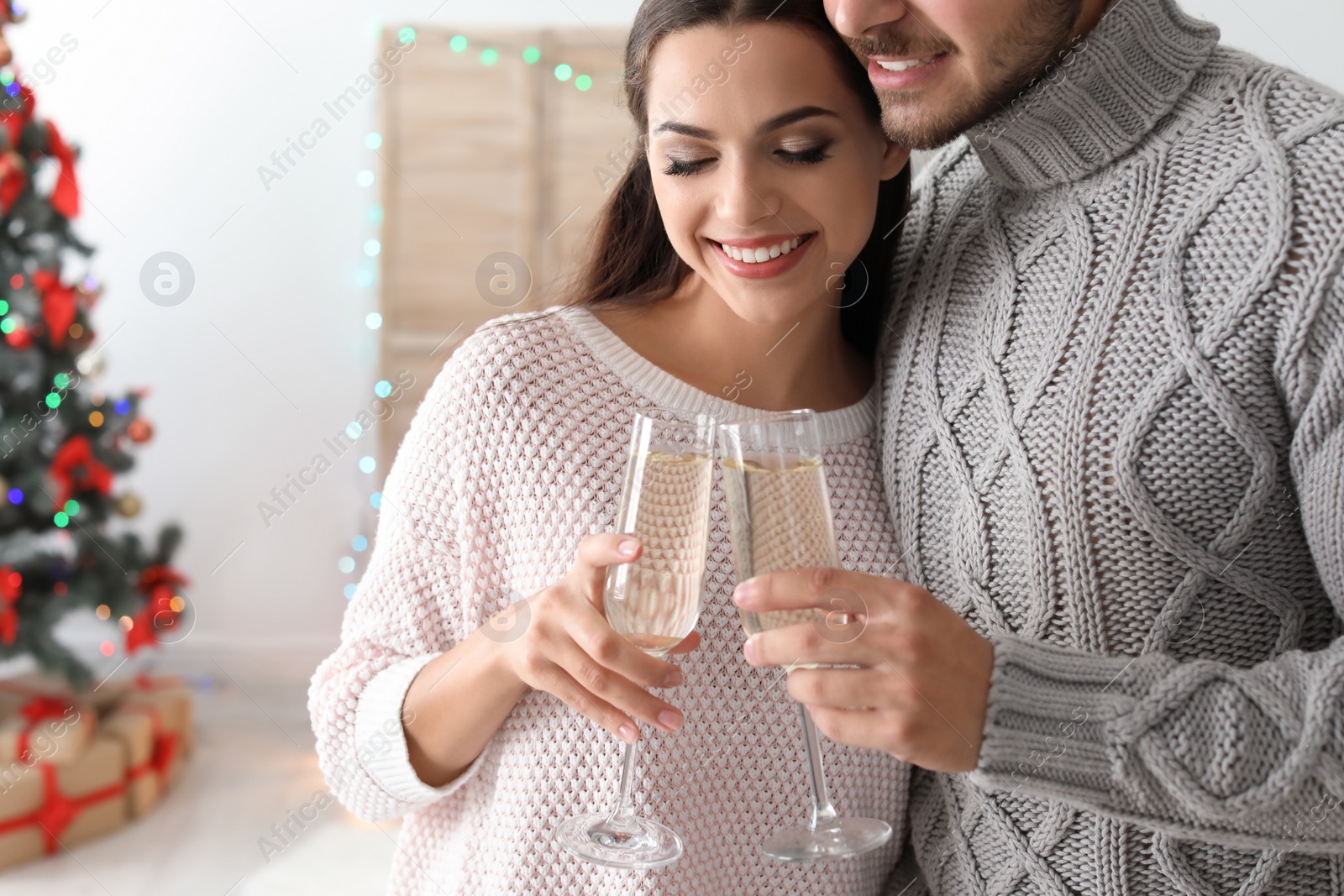 Photo of Happy young couple with glasses of champagne celebrating Christmas at home