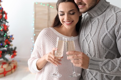 Happy young couple with glasses of champagne celebrating Christmas at home