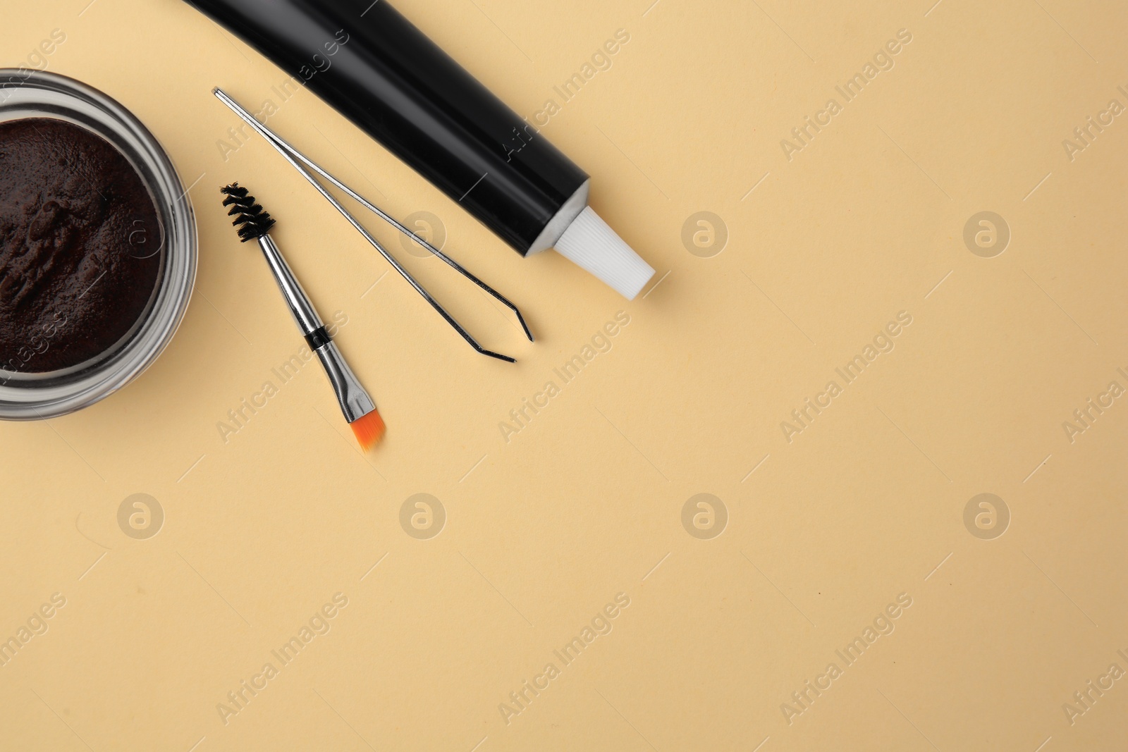 Photo of Flat lay composition with eyebrow henna and tools on beige background. Space for text