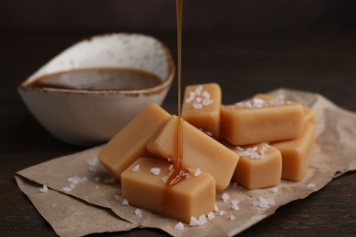 Photo of Pouring caramel on candies with sea salt at table, closeup