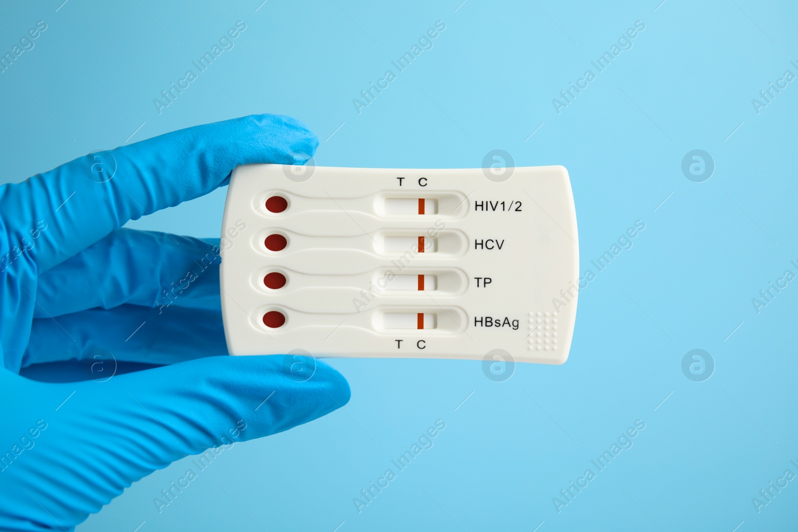 Photo of Doctor holding disposable express test for hepatitis on light blue background, closeup