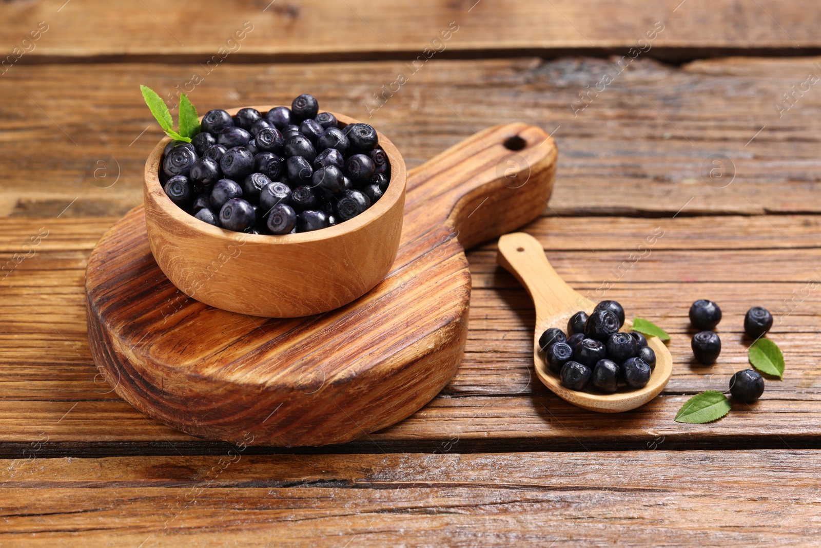 Photo of Ripe bilberries and leaves on wooden table