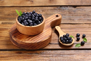 Photo of Ripe bilberries and leaves on wooden table