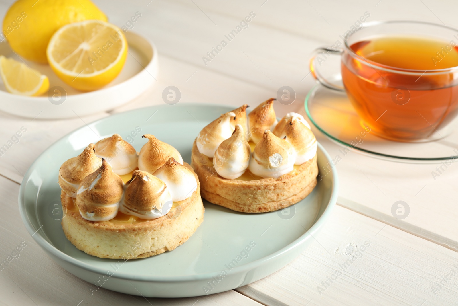 Photo of Delicious lemon meringue pies on white wooden table