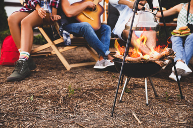 Friends resting together near bonfire, closeup view. Camping season