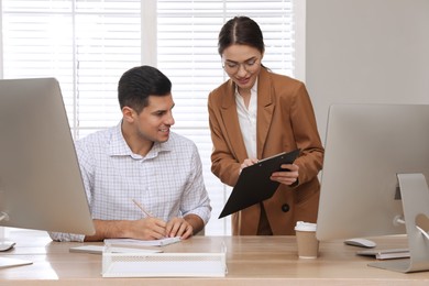 Businesswoman helping intern with work in office