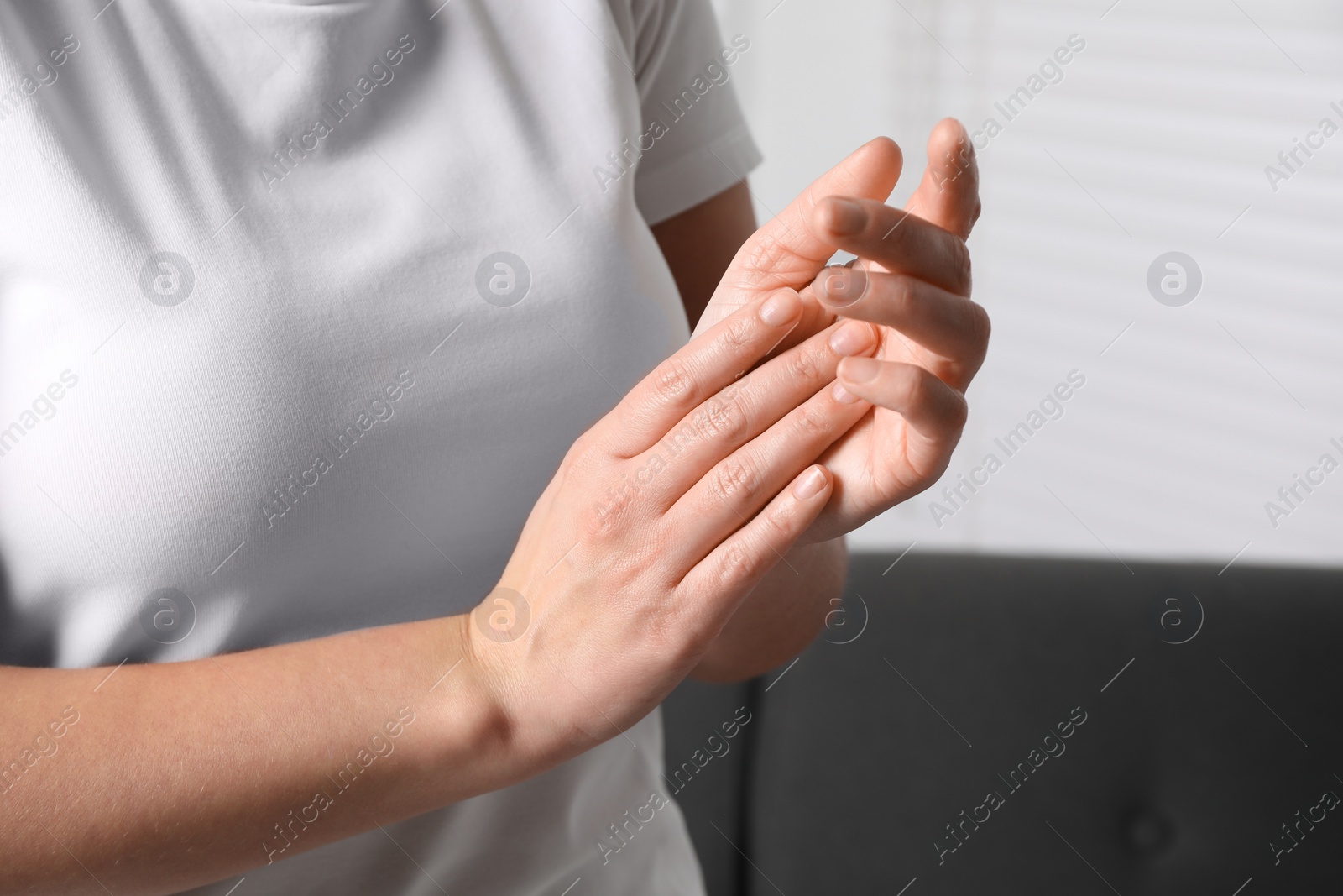 Photo of Woman applying cosmetic cream onto hand on blurred background, closeup