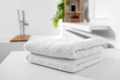 Photo of Stacked soft towels on white table in bathroom