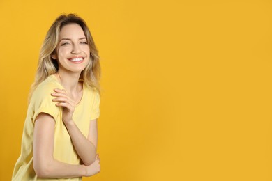 Photo of Portrait of happy young woman with beautiful blonde hair and charming smile on yellow background. Space for text