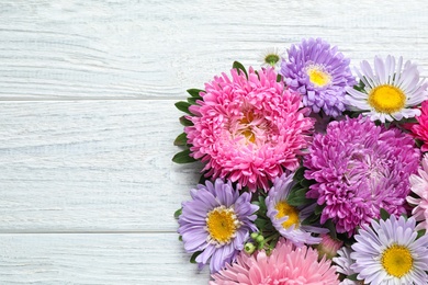 Photo of Flat lay composition with beautiful aster flowers on white wooden table. Space for text