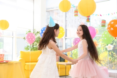 Cute girls playing together at birthday party indoors