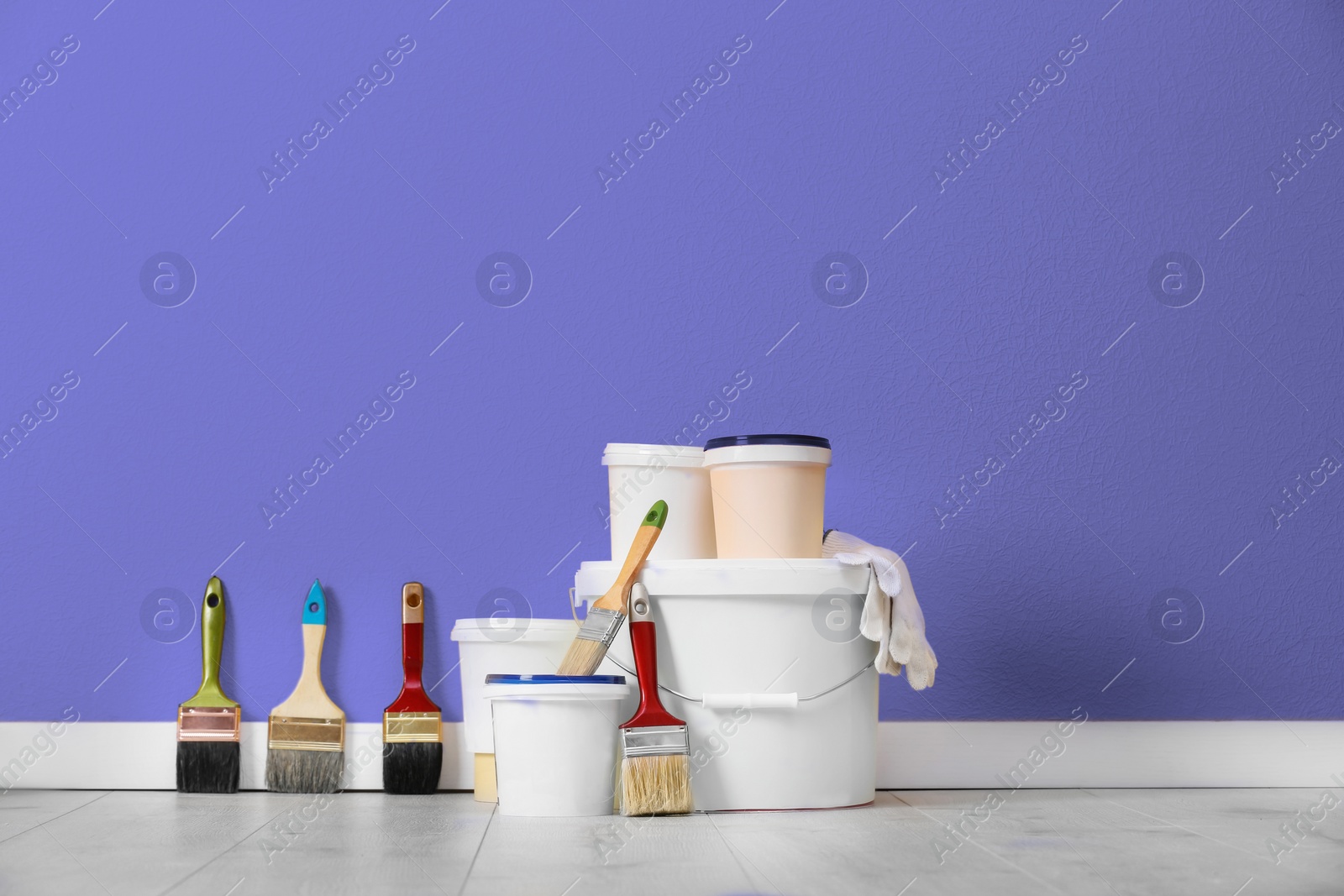 Image of Set with decorator tools and paint on floor near violet wall