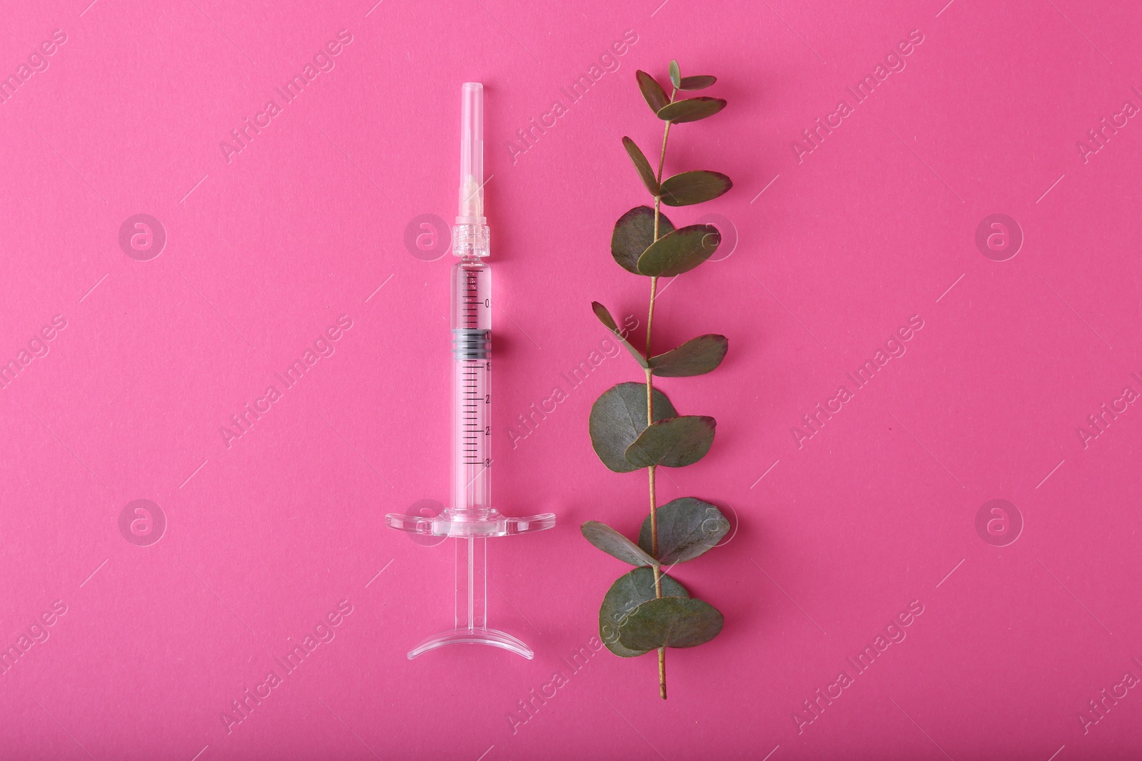 Photo of Cosmetology. Medical syringe and eucalyptus branch on pink background, flat lay