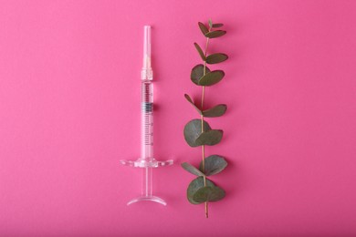 Photo of Cosmetology. Medical syringe and eucalyptus branch on pink background, flat lay