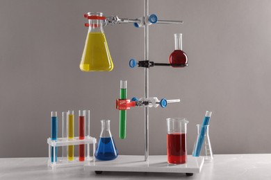 Photo of Retort stand and laboratory glassware with liquids on table against light grey background